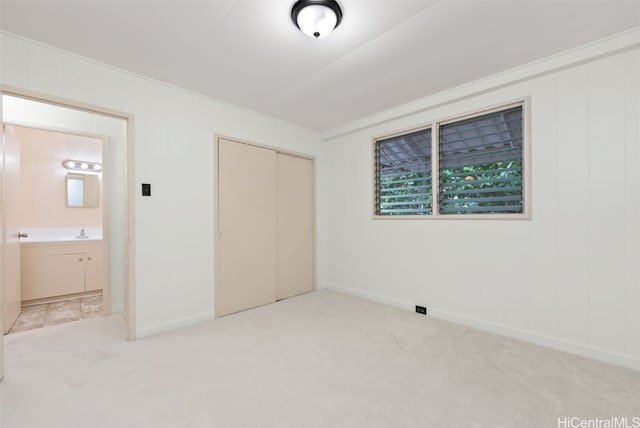 unfurnished bedroom featuring carpet floors, a closet, a sink, and baseboards