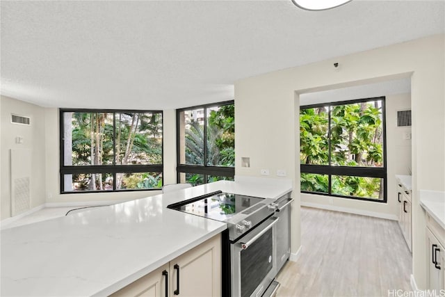 kitchen with visible vents, baseboards, stainless steel electric range oven, light stone countertops, and light wood-style floors