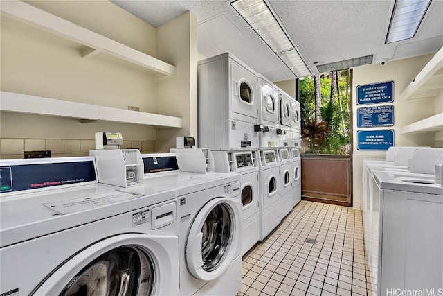 community laundry room featuring light tile patterned flooring, stacked washer and clothes dryer, a textured ceiling, and independent washer and dryer