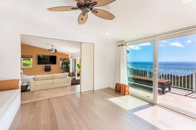 living area featuring baseboards, lofted ceiling, ceiling fan, wood finished floors, and a wall of windows