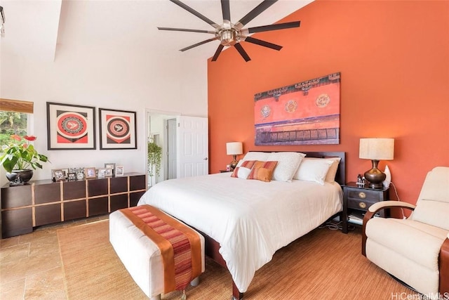 bedroom with a high ceiling, stone finish floor, and a ceiling fan