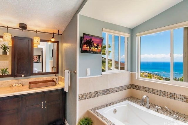 bathroom with vaulted ceiling, a tub to relax in, vanity, and a healthy amount of sunlight