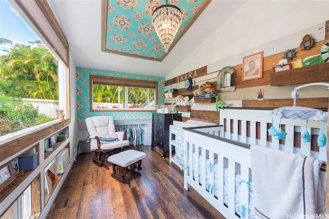 bedroom featuring lofted ceiling, wallpapered walls, an inviting chandelier, and wood finished floors