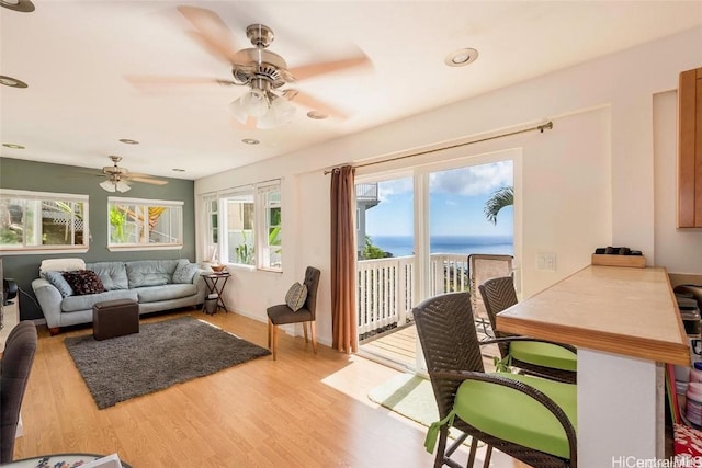 sunroom with ceiling fan and a water view