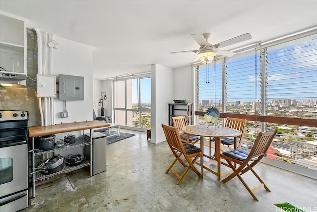 dining space with concrete flooring, expansive windows, electric panel, and a ceiling fan