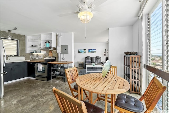 dining area featuring ceiling fan, concrete floors, electric panel, and a healthy amount of sunlight