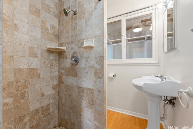 bathroom with tiled shower and wood finished floors