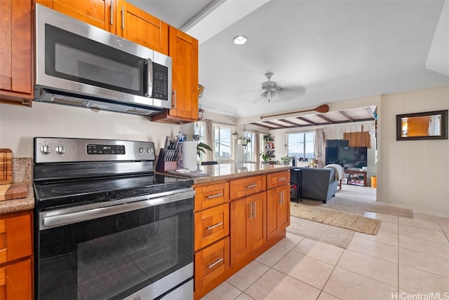 kitchen with ceiling fan, light tile patterned flooring, open floor plan, appliances with stainless steel finishes, and brown cabinets