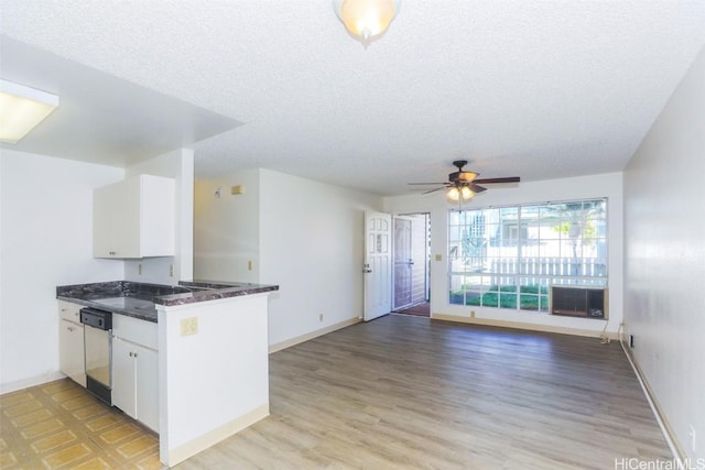 kitchen with a textured ceiling, dishwashing machine, a peninsula, white cabinetry, and light wood-type flooring