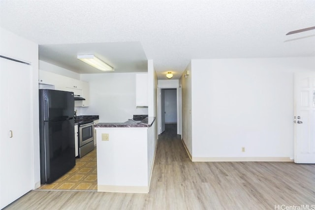 kitchen with electric range, white cabinetry, freestanding refrigerator, light wood finished floors, and dark countertops