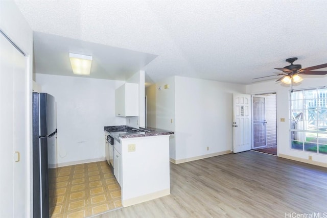 kitchen with light wood-style floors, freestanding refrigerator, white cabinetry, a textured ceiling, and baseboards