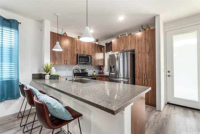 94-1251 Hale Halawai Dr Unit 6, Waipahu, HI 96797 - kitchen featuring stainless steel appliances, a sink, brown cabinets, a peninsula, and a breakfast bar area