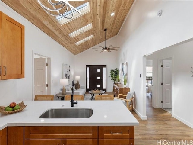 kitchen featuring light countertops, brown cabinetry, wood ceiling, and a sink