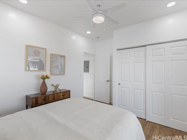 bedroom with a ceiling fan, wood finished floors, electric panel, recessed lighting, and a closet