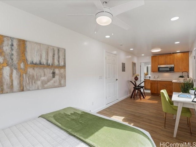 bedroom with electric panel, recessed lighting, wood finished floors, and baseboards