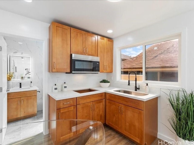 kitchen featuring stainless steel microwave, light countertops, recessed lighting, black electric cooktop, and a sink