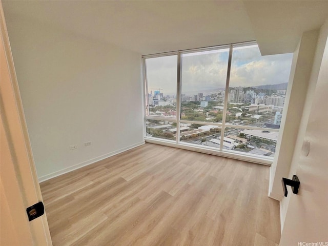 1296 Kapiolani Blvd Unit Ii-2509E, Honolulu, HI 96814 - spare room with floor to ceiling windows, a view of city, wood finished floors, and baseboards