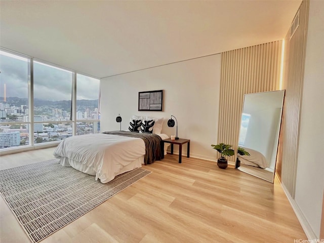 1296 Kapiolani Blvd Unit Ii-2509E, Honolulu, HI 96814 - bedroom with light wood-style flooring, baseboards, expansive windows, and a view of city