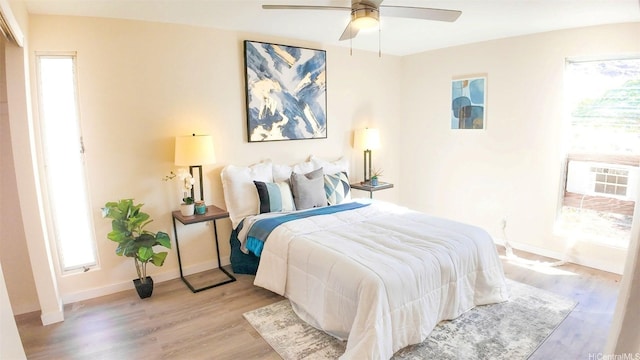 1296 Kapiolani Blvd Unit Ii-2509E, Honolulu, HI 96814 - bedroom featuring light wood-style floors, multiple windows, baseboards, and ceiling fan