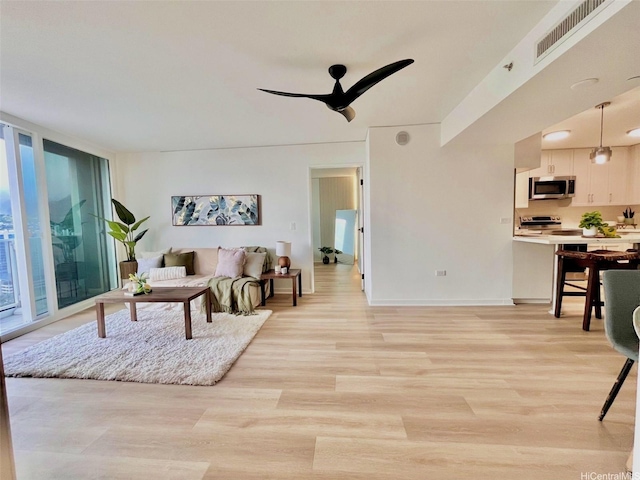 1296 Kapiolani Blvd Unit Ii-2509E, Honolulu, HI 96814 - living room with light wood-style flooring, a ceiling fan, baseboards, and floor to ceiling windows