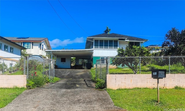 view of front of house with driveway, a fenced front yard, an attached carport, and stucco siding