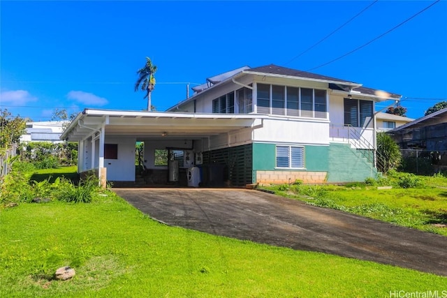 rear view of house featuring a yard, aphalt driveway, and an attached carport