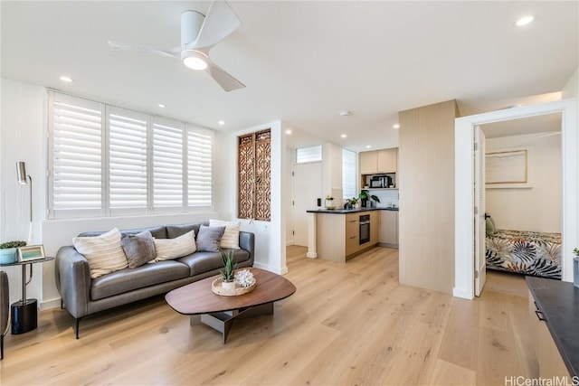 living area with light wood-style floors, a ceiling fan, and recessed lighting