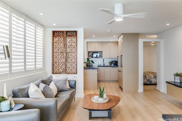 living room featuring a ceiling fan, light wood-type flooring, and plenty of natural light