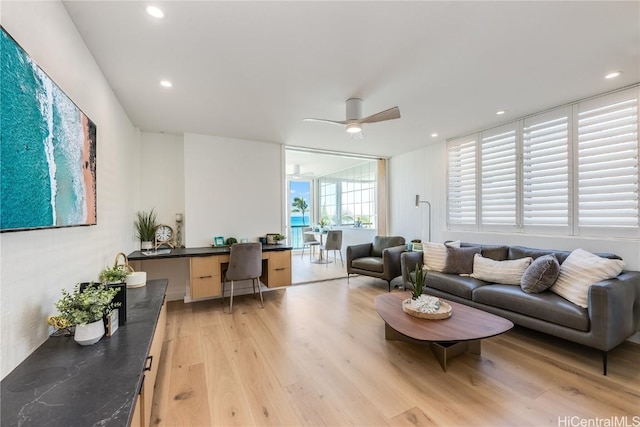 living room with ceiling fan, built in study area, light wood-style flooring, and recessed lighting