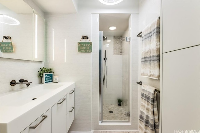 bathroom featuring vanity, backsplash, a shower stall, and tile walls