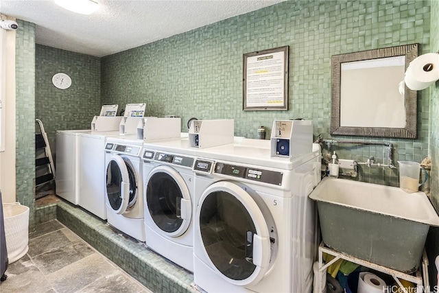 community laundry room featuring washing machine and dryer, a sink, and a textured ceiling