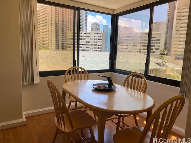 dining space featuring a city view, baseboards, and wood finished floors