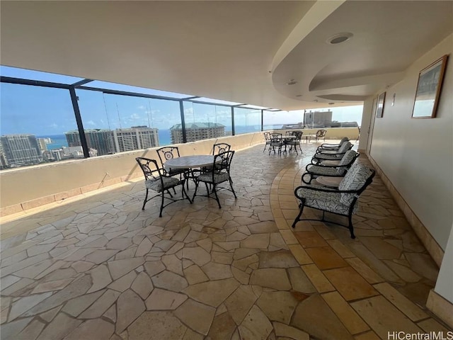 view of patio with a view of city, outdoor dining area, and glass enclosure