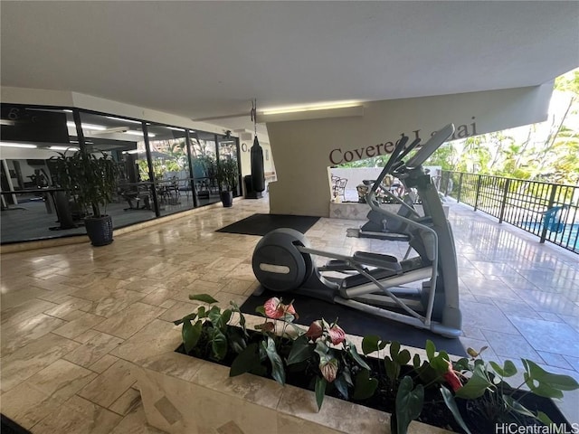 exercise room featuring stone tile flooring and a wealth of natural light