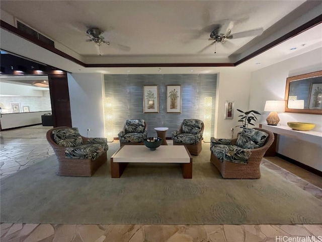 sitting room with visible vents, a raised ceiling, and a ceiling fan