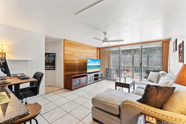 living room featuring wooden walls, ceiling fan, expansive windows, and light tile patterned flooring