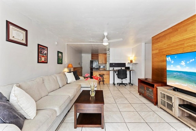 living area featuring wood walls, a ceiling fan, and light tile patterned flooring