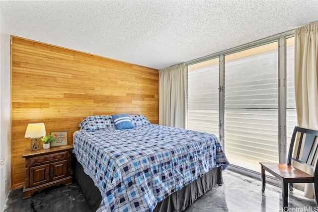 bedroom featuring a textured ceiling and wooden walls