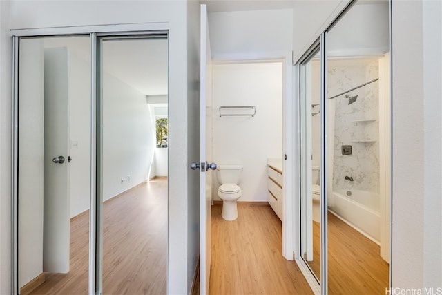 bathroom featuring toilet, shower / tub combination, wood finished floors, and vanity