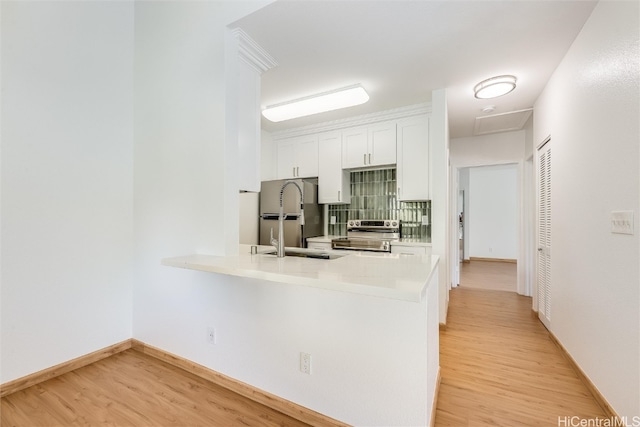 kitchen with stainless steel appliances, light countertops, light wood-style flooring, and white cabinets