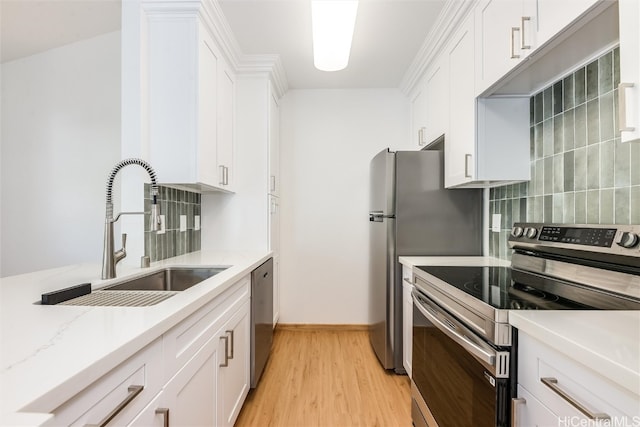 kitchen featuring stainless steel appliances, a sink, white cabinetry, light wood-style floors, and decorative backsplash