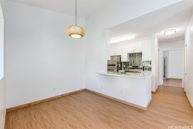 kitchen featuring pendant lighting, light wood-style floors, appliances with stainless steel finishes, white cabinetry, and a sink