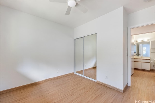 unfurnished bedroom with light wood-type flooring, a closet, ceiling fan, and baseboards