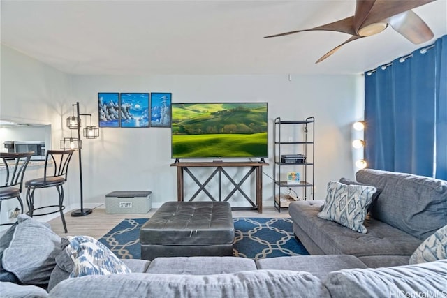 living room with ceiling fan, baseboards, and wood finished floors