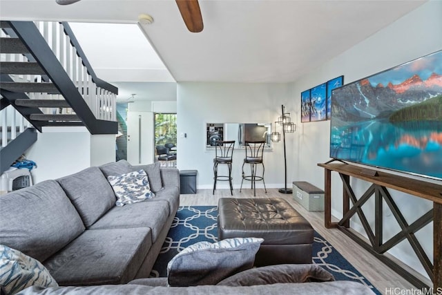 living room with ceiling fan, stairway, wood finished floors, and baseboards