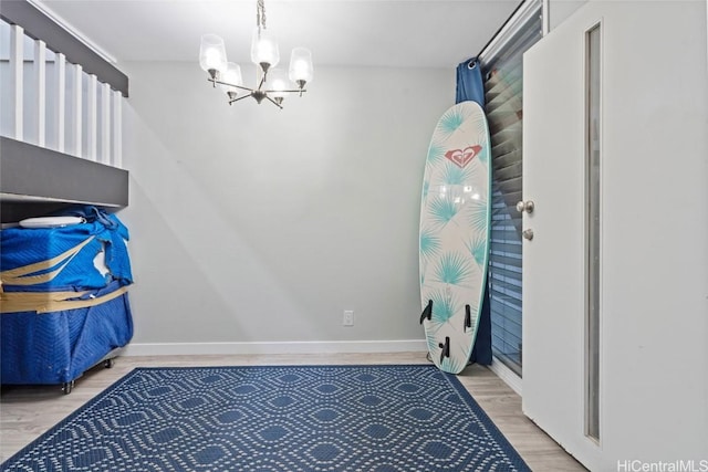 interior space featuring baseboards, light wood-style flooring, and a notable chandelier