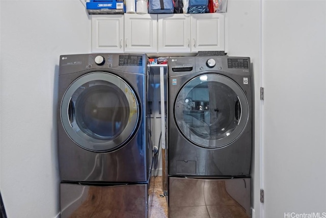 clothes washing area featuring washing machine and dryer, tile patterned flooring, and cabinet space