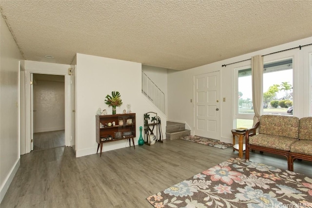 foyer featuring stairway, a textured ceiling, and wood finished floors