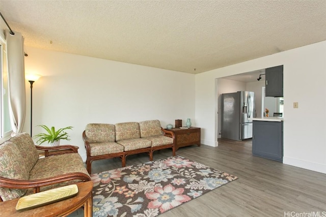 living room with a textured ceiling, baseboards, and wood finished floors