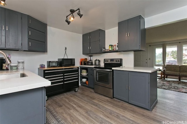 kitchen with stainless steel electric range, black microwave, light countertops, and a sink